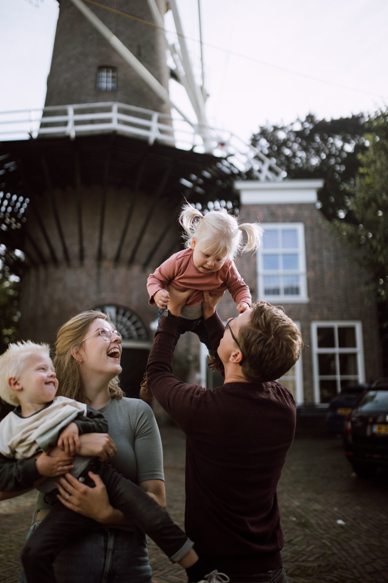 Lotte met haar gezin voor een molen in Gouda. Lotte heeft haar zoontje vast en haar man heeft hun dochter vast.