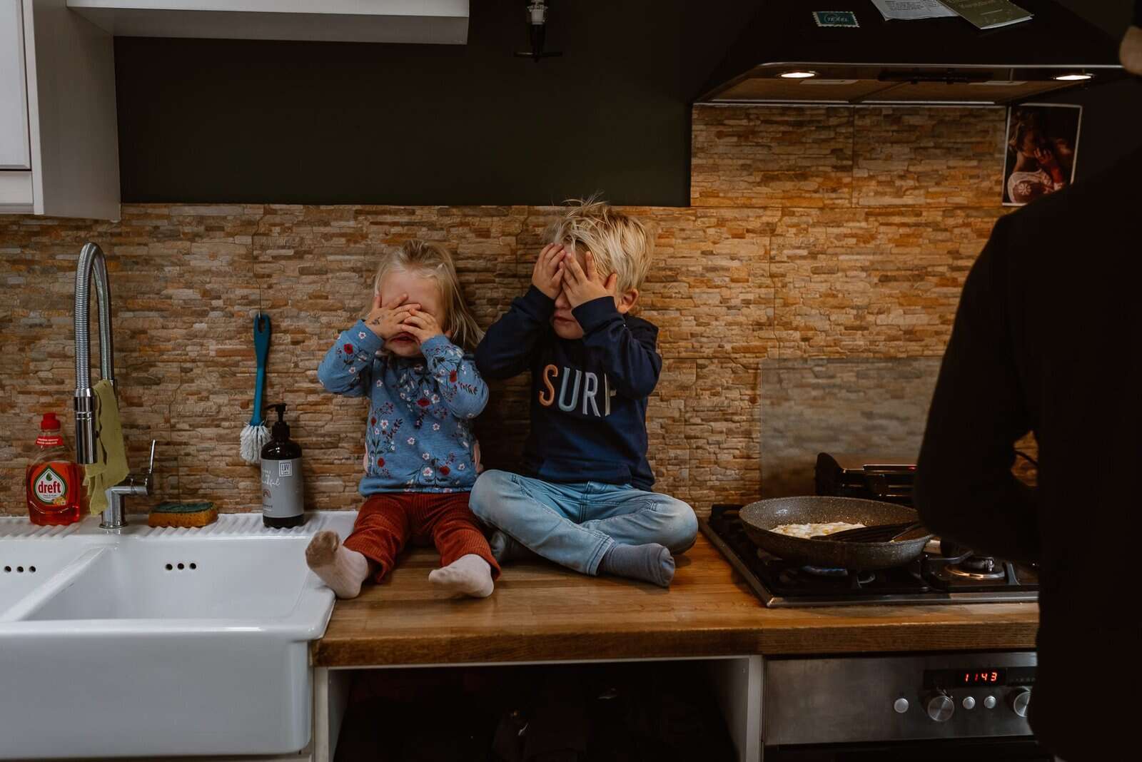 De Rooij | LA Fotografie-98 Rechts is de rug van de kraamverzorgster zichtbaar. Ze legt aan papa en mama uit hoe warm het badwater moet zijn. Papa staat met het bad in zijn hand, klaar om in de badkamer te vullen. Mama staat met Hidde van 4 dagen oud te luisteren en te wachten tot ze hem voor het eerst in bad kan doen.