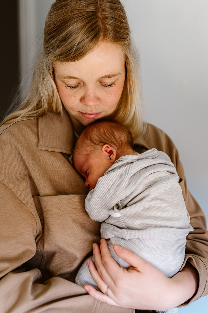 Man en zwangere vrouw in de felle zon. Staan dicht tegen elkaar aan en raken beiden de zwangere buik aan.